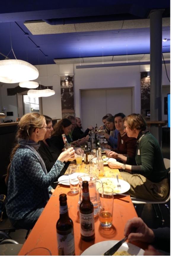 A picture of a long table with lots of people talking and eating