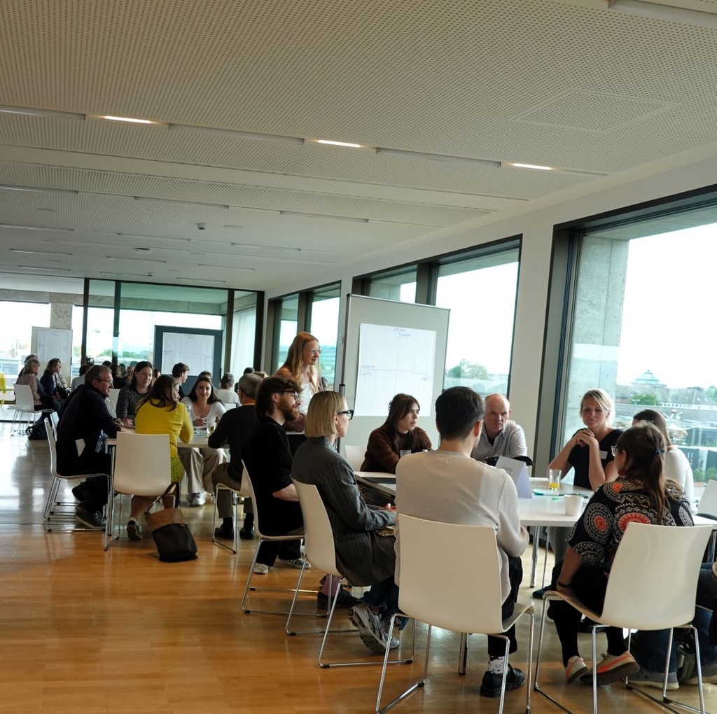 Picture of people sitting at desks and discussing in groups