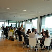 Picture of people sitting at desks and discussing in groups